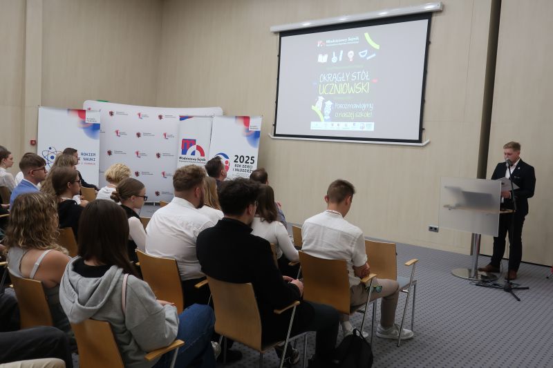 Publiczność patrząca na mężczyznę przemawiającego przy mównicy
