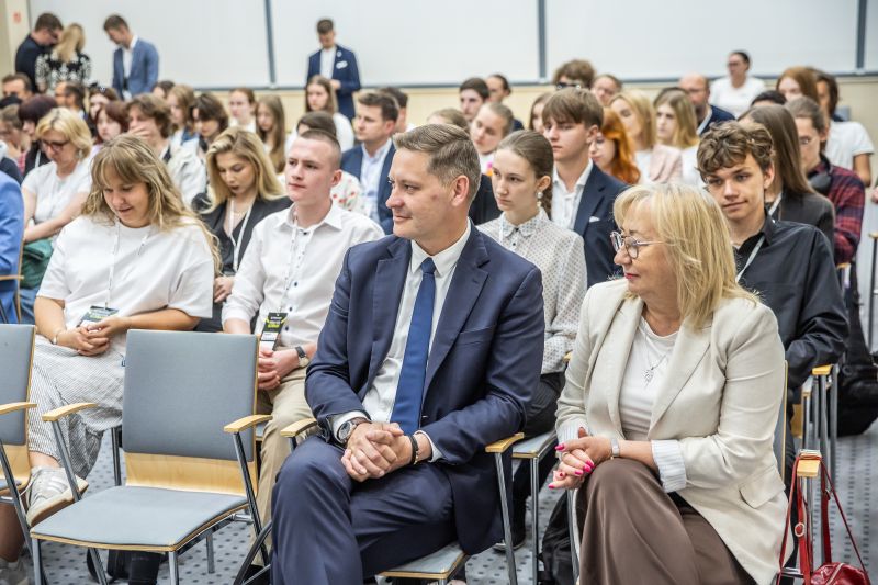 Publiczność patrząca na mężczyznę przemawiającego przy mównicy