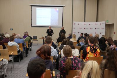 Mężczyzna w czarnej koszuli przemawiający do zebranych