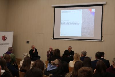 Troje mężczyzn siedzących na wprost do publiczności rozmawia na temat puszczanej prezentacji