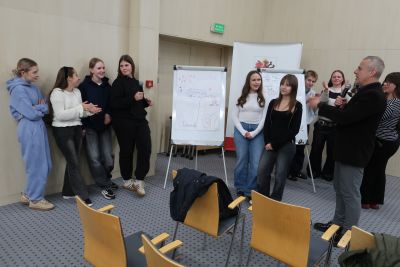 Uczniowie pozujący do zdjęcia z flip chartem