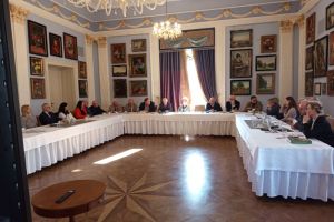 widok sali, stół w kształcie litery u, osoby siedzą za stołem